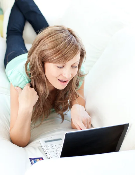Glada blond kvinna som tittar på sin laptop i soffan — Stockfoto