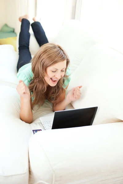 Mulher caucasiana entusiasmada olhando para seu laptop no sofá — Fotografia de Stock