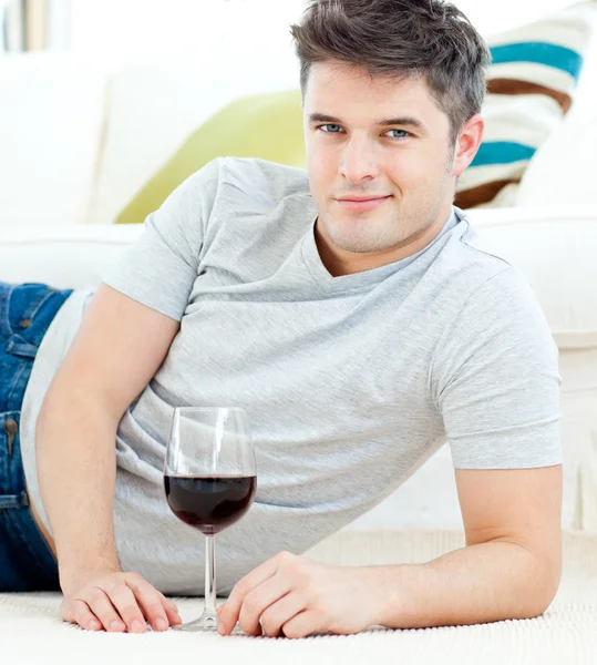 Pohledný mladý muž s skleničku, ležící na podlaze — Stock fotografie