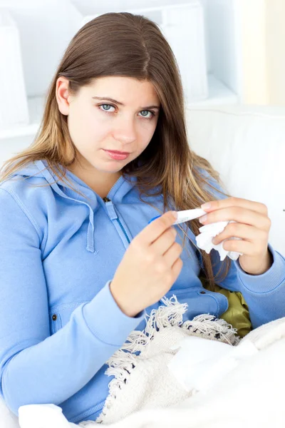 Sick woman holding tissues sitting on a sofa — Stock Photo, Image