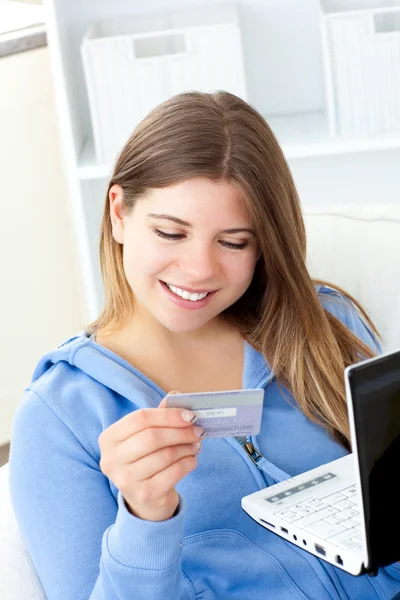 Mujer encantada sosteniendo una tarjeta y un ordenador portátil — Foto de Stock