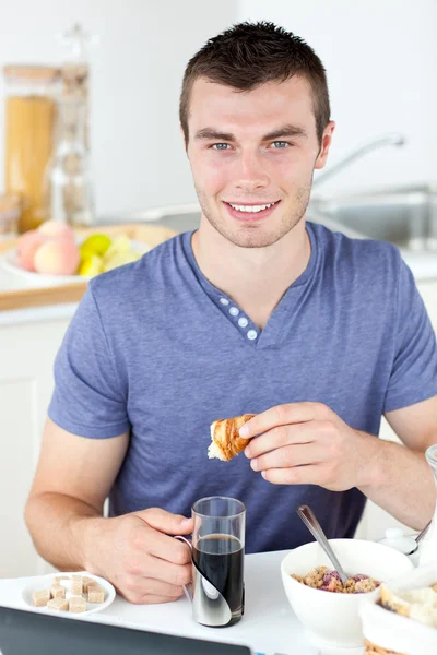 Handsome man eating croissant drinking coffee — Stock Photo, Image