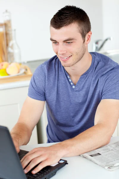 积极的年轻男子在厨房中使用他的笔记本电脑 — 图库照片