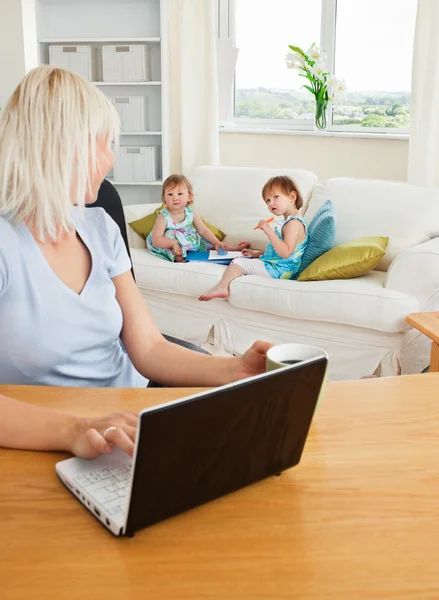 Blond moeder werken op laptop — Stockfoto
