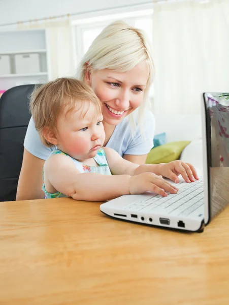 Blond mother and her daughter sitting in front of the laptop — Stock Photo, Image
