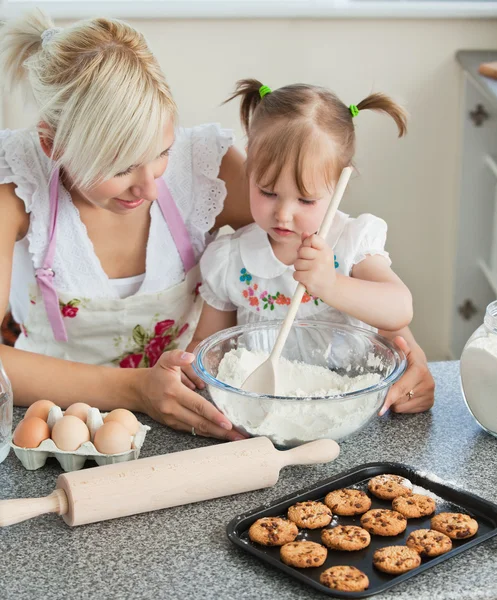 与她的女儿们微笑的女人烘烤饼干 — 图库照片