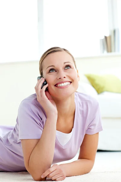 Cheerful young woman talking on phone lying on the floor — Stock Photo, Image