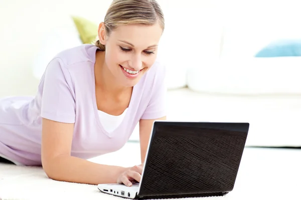 Mulher caucasiana encantada usando seu laptop no chão — Fotografia de Stock