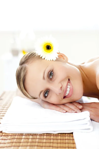 Veselá mladá žena s květinami ve vlasech na masážní stůl — Stock fotografie