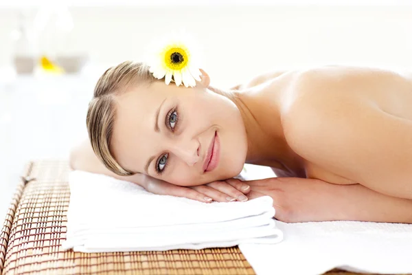 Mujer joven y brillante con flores en el pelo sobre una mesa de masaje —  Fotos de Stock