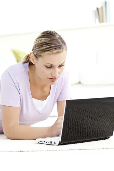 Vrouw met behulp van haar computer op de vloer liggen geconcentreerd — Stockfoto