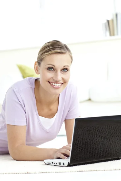 Charming woman using her computer lying on the floor — Stock Photo, Image