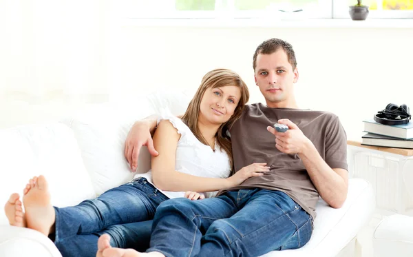 Positiva kaukasisk par tittar på tv liggande på soffan — Stockfoto