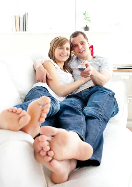 幸福的年轻情侣躺在沙发上看电视 — 图库照片
