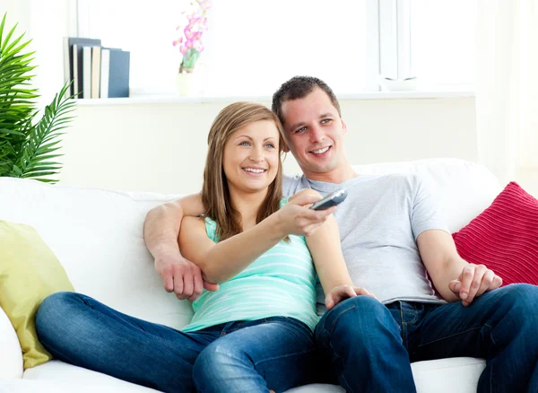 Carismático hombre abrazando a su novia mientras mira la televisión —  Fotos de Stock