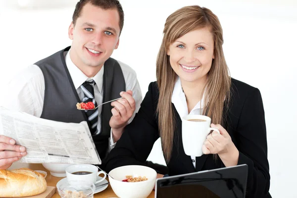 Joyful couple of businesspeople having breakfast smiling at the — Stock Photo, Image