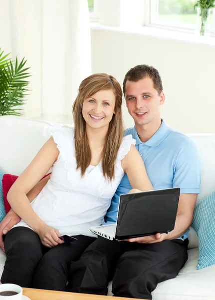Entusiástico casal usando laptop sorrindo para a câmera — Fotografia de Stock