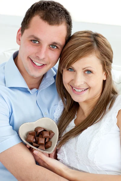 Abrazando pareja sosteniendo chocolate sonriendo a la cámara —  Fotos de Stock