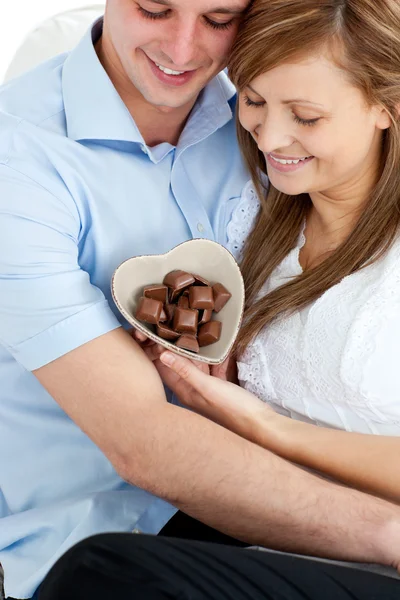 Abraçando casal afetuoso segurando chocolote sentado — Fotografia de Stock