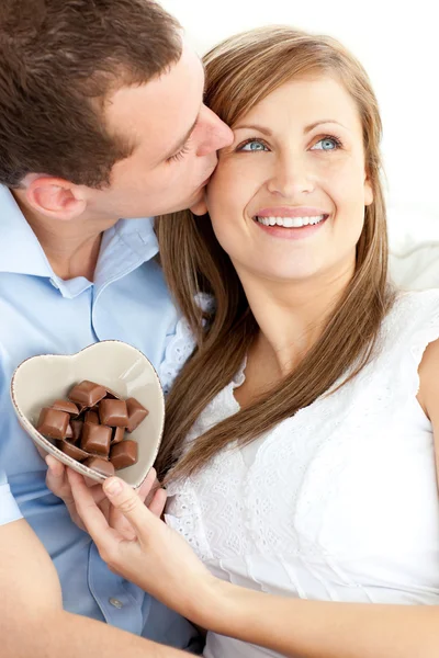 Hombre guapo besando a su novia sosteniendo chocolate —  Fotos de Stock