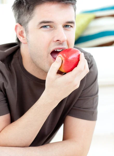 Jovem deitado no chão e comendo uma maçã vermelha — Fotografia de Stock