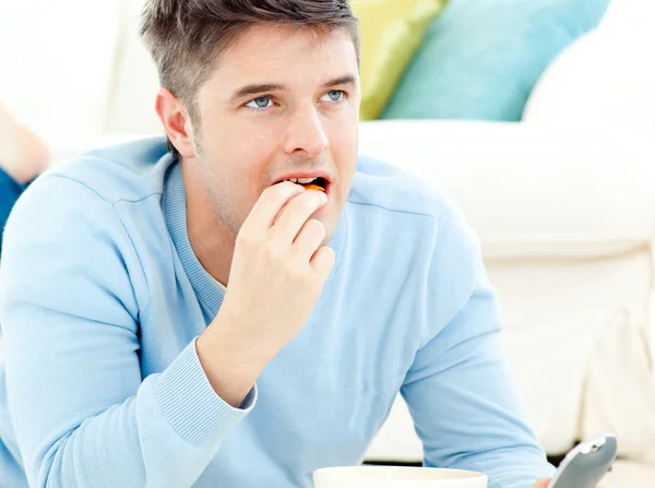 Giovane uomo sdraiato a terra e mangiare una fetta di pizza — Foto Stock