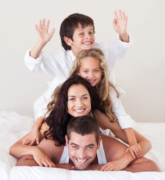 Семья веселится в постели с поднятыми руками — стоковое фото