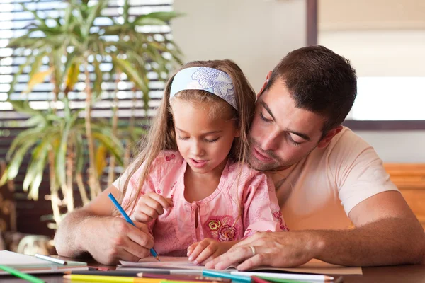 Little girl with her smiling father at the table Stock Image