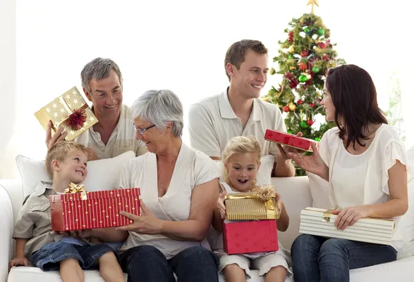 Lycklig familj hemma öppnar julklappar Stockbild