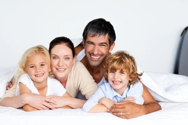 Sonriendo familia juntos en la cama — Foto de Stock