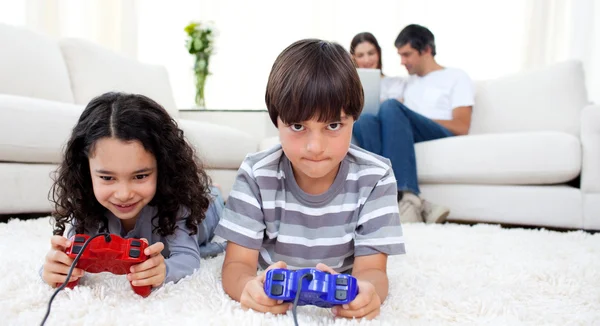 Bedårande syskon spelar TV-spel som ligger på golvet — Stockfoto