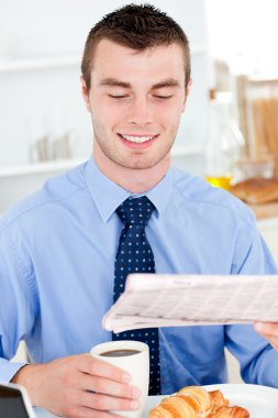 Happy businessman reading the newspaper drinking coffee clipart