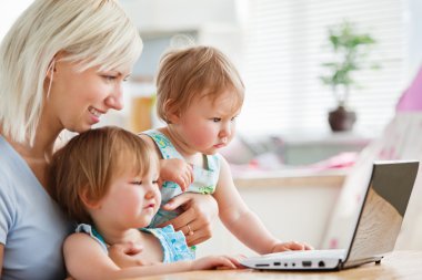 Astonished children looking at a laptop with their mother clipart