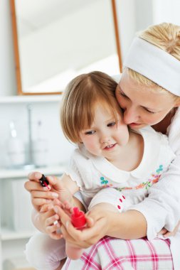 Charming mother making her little daughter's nails clipart