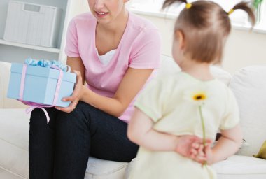 Surprised mother getting a present from her little daughter clipart