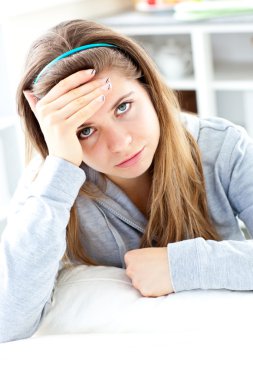 Depressed young woman sitting in the kitchen clipart