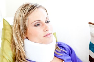 Beautiful woman wearing neckbrace lying on a sofa clipart