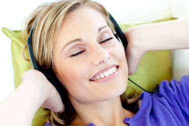 Charming caucasian woman listening to music with headphones lyin clipart