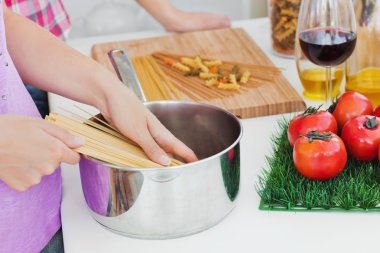 Close-up of two women cooking spaghetti in the kitchen clipart