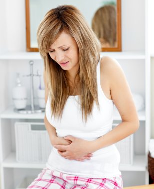 Cute woman having a stomachache in the bathroom clipart