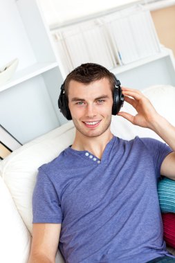 Relaxed young man listening to music with headphones looking at clipart