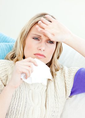 Ill woman holding a tissue sitting on a sofa clipart