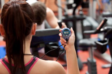 Young woman holding a chronometer and man doing physical exercis clipart