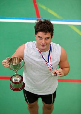 Happy young man holding a trophee and a medal clipart