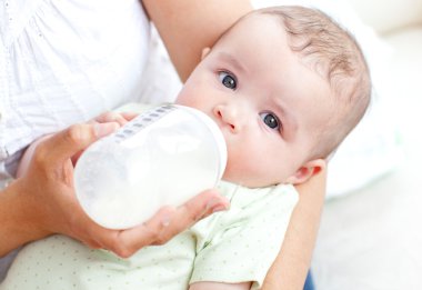 Charming mother feeding her adorable son in the kitchen clipart