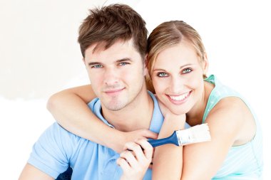 Smiling caucasian couple painting a room clipart