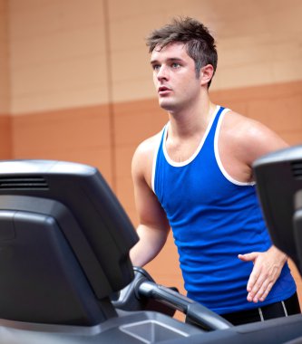 Concentrated athletic man training on a running machine clipart