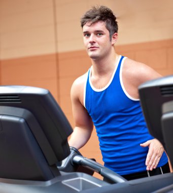 Good-looking man exercising on a running machine clipart