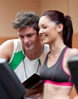 Cheerful athletic woman standing on a running machine with her p clipart