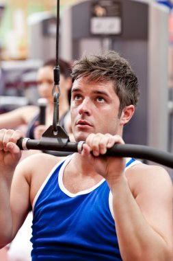 Muscular male athlete practicing body-building in a fitness center clipart